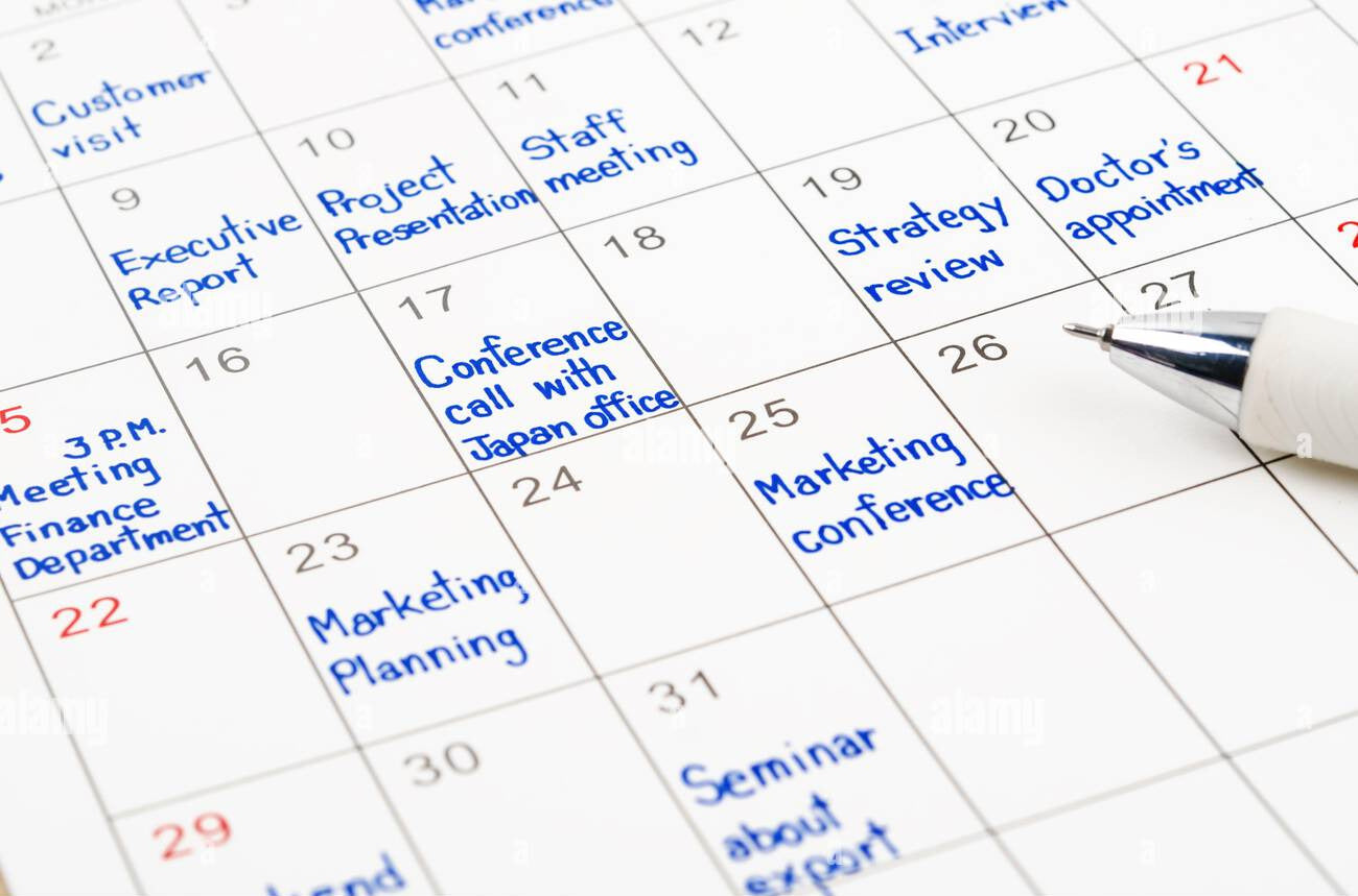 Calendar with appointments marked and a pen on a white background